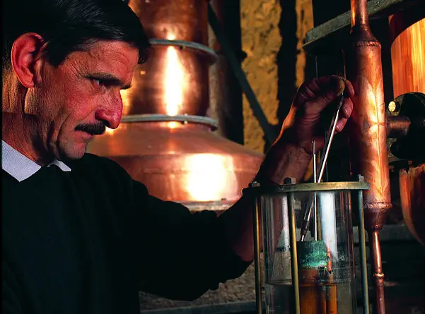 Distiller checking the spirit at the copper Armagnac still