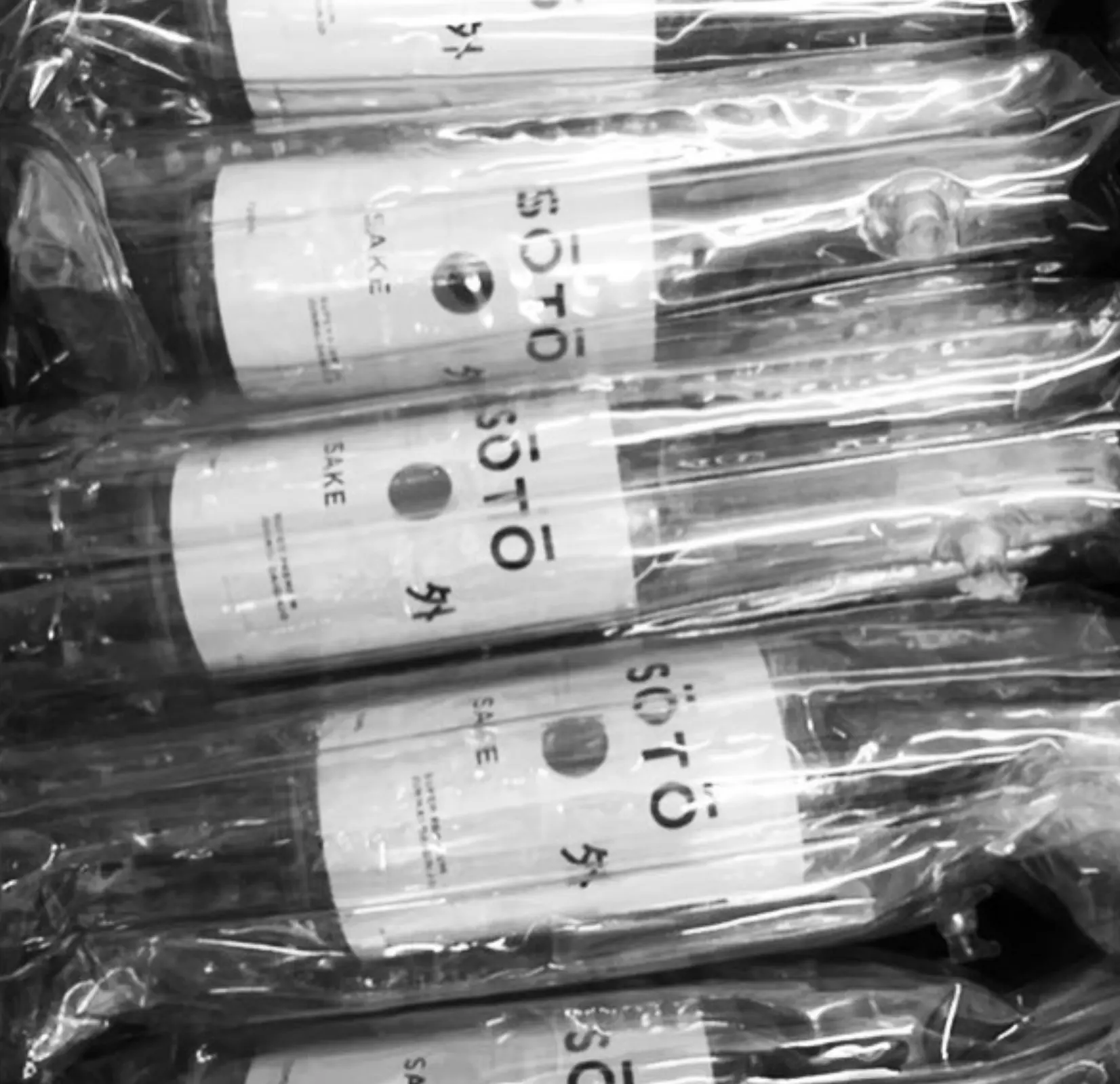 Bottles of SŌTŌ sake lying down, black and white