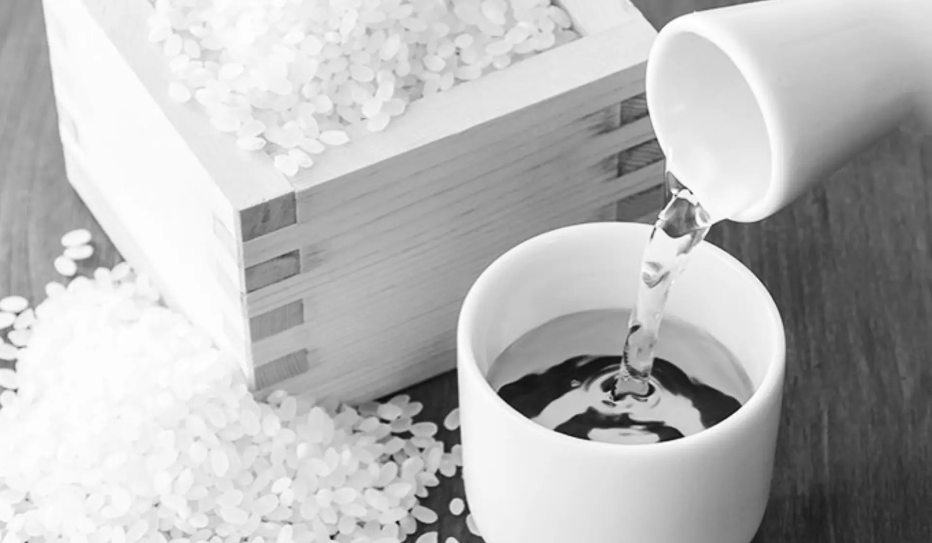 Sake being poured into a wooden masu box with rice