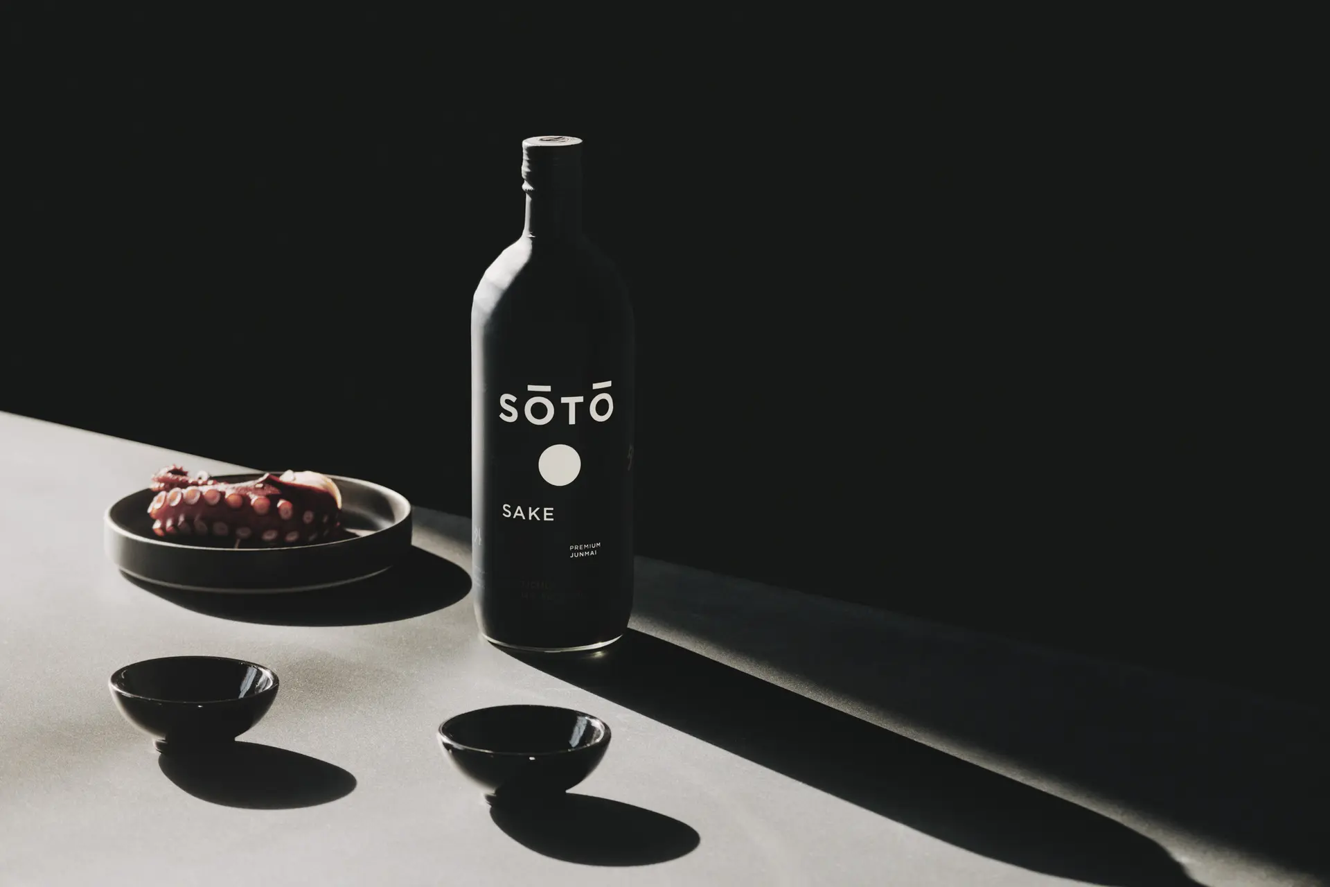 Flasche SŌTŌ Sake mit Schalen im Streiflicht